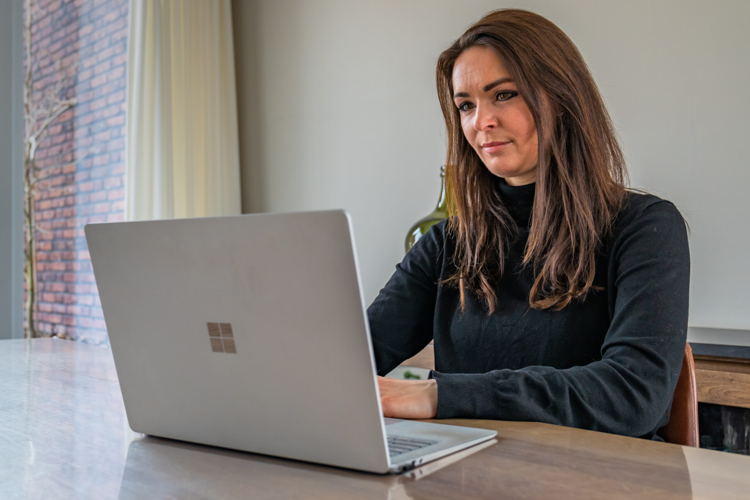 Alanna Meijers aan tafel achter haar laptop bij een artikel over kinderalimentatie en het LBIO